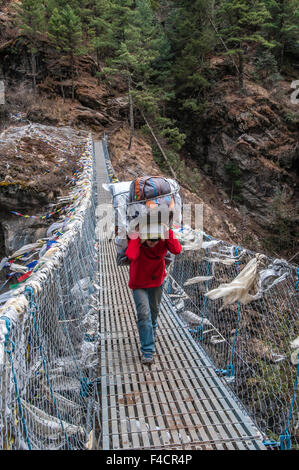 Giovani porter attraversando ponte di sospensione, Nepal. Foto Stock