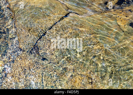 Dettaglio astratto, visto da sopra, di un ruscello che scorre sulla roccia e piccoli ciottoli causando l'acqua ripple e creare un pattern. Inghilterra, Regno Unito Foto Stock