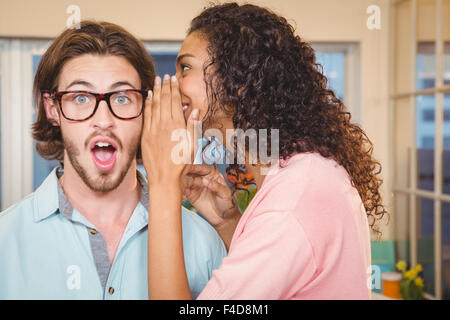 Imprenditrice whispering in collega di sesso maschile orecchio Foto Stock