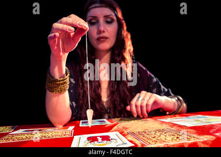 Femmina di fortune teller holding pendolo con gli occhi chiusi Foto Stock