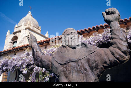 Un scolpito a mano statua in legno di Padre Junipero Serra sorge nel Carmelo, California, Stati Uniti d'America, di fronte la Chiesa della Basilica della Missione di San Carlo Borromeo de Carmelo, che il frate francescano fondato nel 1771. Il leggendario sacerdote spagnolo divenne una santa cattolica quando canonizzata da Papa Francesco nel mese di settembre, 2015. Il Carmel Mission è stata la seconda di 21 missioni della California ha stabilito in alto e in basso lo stato; è stato uno dei nove fondata da San Serra. Egli vi morì nel1784 all'età di 70 ed è sepolto sotto il santuario piano. Foto Stock