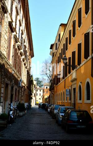 Automobili parcheggiate lungo una tranquilla strada stretta in Roma, Italia Foto Stock