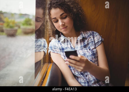 Piuttosto studente seduto dalla finestra utilizzando il telefono Foto Stock