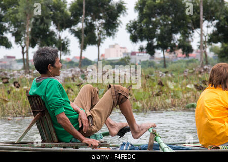 Uomo vietnamita le righe con i piedi la barca turistica lungo ngo dong river a Tam Coc,Ninh Binh,Vietnam Foto Stock