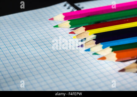 Matite colorate giacente su un notebook aperto Foto Stock
