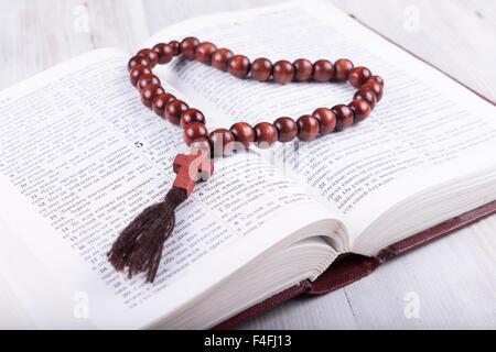 Tema Religioso libro sacro e la croce su un bianco sullo sfondo di legno Foto Stock