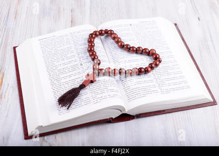 Tema Religioso libro sacro e la croce su un bianco sullo sfondo di legno Foto Stock