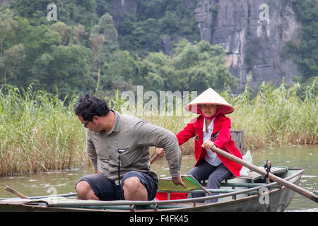 Signora vietnamita righe turista maschio in canotto lungo ngo dong river Tam Coc verso le tre grotte, Ninh Binh,Vietnam Foto Stock