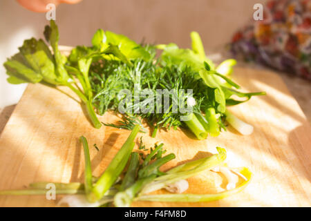 Il prezzemolo e l'aneto sul tagliere di legno. Preparazione di insalata di verdure e ortaggi freschi/insalata fresca con olio d'oliva Foto Stock