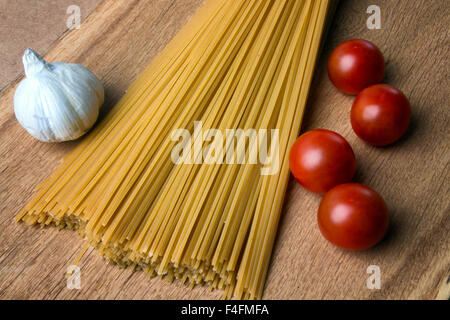 Aglio, i pomodorini cotte e di spaghetti su una tavola di legno Foto Stock