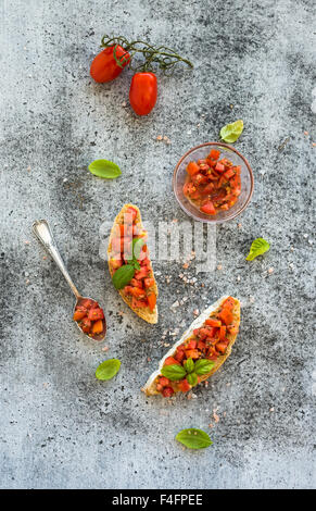 Pomodoro e Basilico bruschetta sandwich grunge su uno sfondo grigio, vista dall'alto Foto Stock