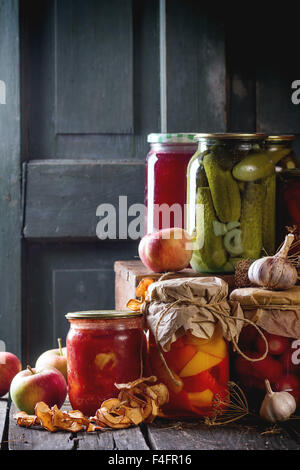 Collezione insieme di molti in casa vasi di vetro con conserve alimentari (cetrioli e pomodori e peperoni), con aglio e freschi ed essiccati a Foto Stock