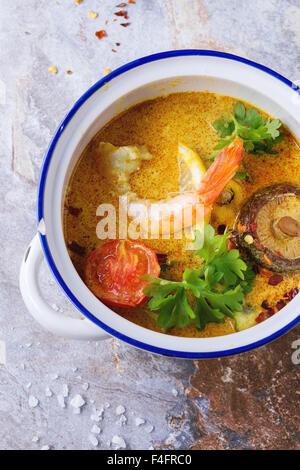 In ceramica bianca con pan piccante zuppa tailandese Tom Yam con latte di cocco, peperoncino e gamberetti oltre la pietra grigia sullo sfondo. Vista superiore Foto Stock