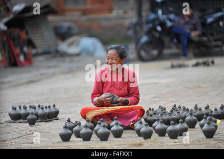 Kathmandu, Nepal. Xvii oct, 2015. Una donna Nepalese sorrisi come lei dispone di pentole di fango per essiccazione a ceramica quadrata in Bhaktapur. Bhaktapur è una città antica nella valle di Kathmandu e viene elencato come un sito del Patrimonio Culturale Mondiale dell UNESCO per la sua ricca cultura, templi e il legno, il metallo e la pietra opere d'arte. © Narayan Maharjan/Pacific Press/Alamy Live News Foto Stock