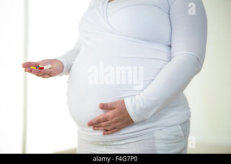 Donna incinta prendendo pillola medica Foto Stock