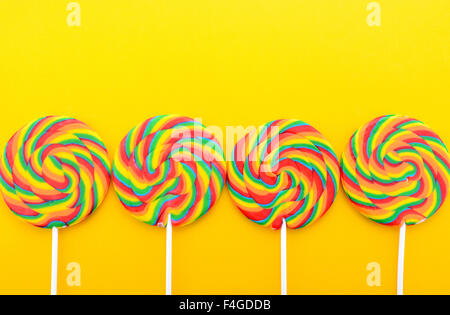 Bright rainbow lollipop candy sulla colorata giallo tavolo in legno per la festa di Halloween Dolcetto o Scherzetto o Festa per bambini. Foto Stock