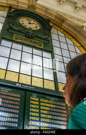 La donna legge l'orario del treno a bordo alla stazione ferroviaria di Sao Bento. Ottobre, 2015. Porto, Portogallo Foto Stock