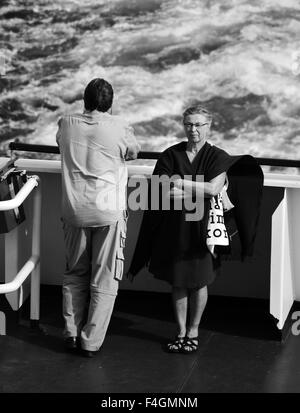 Un uomo e una donna sul retro di una imbarcazione, rivolta lontano da ogni altro, in bianco e nero Foto Stock