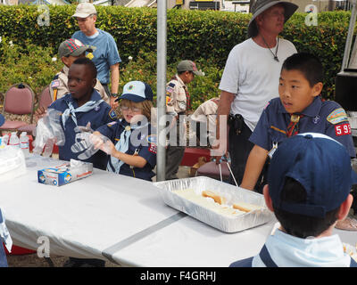 Nero, bianco e Oriental boyscouts preparare hot dogs per le forze di polizia in fiera. Redondo Beach, CA. Foto Stock