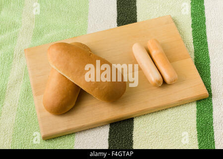 La salsiccia e pane giacciono su di un tagliere di legno Foto Stock