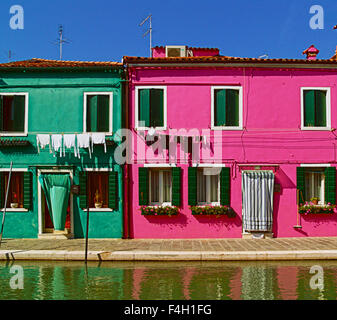 Burano, Italia, verde e rosa case dipinte con landry appeso e tende da sole Foto Stock