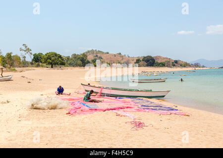 I pescatori locali riassettavano le reti da pesca sulla Scenic lake shore, Kaya Mawa, Likoma Island, il Lago Malawi Malawi, sud-est Africa Foto Stock