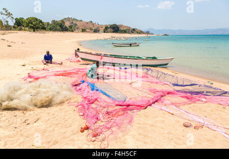 I pescatori locali riassettavano le reti da pesca sulla soleggiata sul lago, Kaya Mawa, Likoma Island, il Lago Malawi Malawi, sud-est Africa Foto Stock