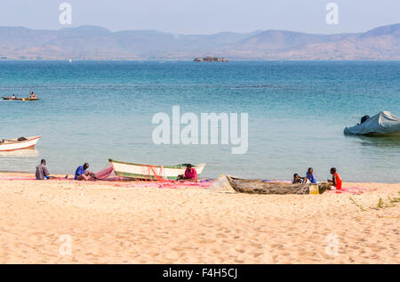 I pescatori locali riassettavano le reti da pesca in riva al lago, Kaya Mawa, Likoma Island, il Lago Malawi Malawi, sud-est Africa Foto Stock