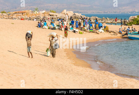 La popolazione locale lo scarico di merci da una barca sul lago spiaggia, Likoma Island, il Lago Malawi Malawi, sud-est Africa Foto Stock