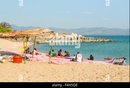 I pescatori locali riassettavano le reti da pesca sulla soleggiata spiaggia sul lago, Likoma Island, il Lago Malawi Malawi, sud-est Africa Foto Stock