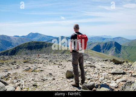 Un maschio escursionista escursionismo da soli su Carnedd Dafydd mountain top in montagne Carneddau guarda a vista distante Snowdon nel Parco Nazionale di Snowdonia Wales UK Foto Stock