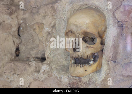 Cranio umano murata nel muro di pietra Foto Stock