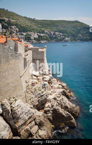 Dubrovnik, Dubrovnik-Neretva County, Croazia. Visitatori sulla passeggiata delle mura della città vecchia. Cafe sotto le mura. La città vecchia Foto Stock