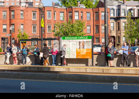 La gente in attesa di un treno in arrivo presso la Brigham Circle stazione sul MBTA Huntington Avenue linea di Boston, Massachusetts. Foto Stock