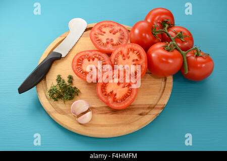 Affettato e pomodori interi con aglio e timo, pronto per il forno la tostatura con un coltello di pomodoro Foto Stock
