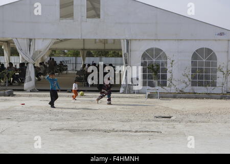 Atene, Grecia. Xviii oct, 2015. Una donna e i suoi figli a piedi passato la tenda sono stati gli altri rifugiati hanno il pranzo. Volontari da Grecia, nonché espatriata e ai visitatori di Grecia visita il Elaionas Refugee Camp su una base regolare per fornire un programma per bambini, per i bambini che soggiornano in campo per un paio di giorni su una sosta sulla loro strada verso l'Europa occidentale. © Michael Debets/Pacific Press/Alamy Live News Foto Stock