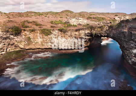 Splendide costiere di calcare formazione di roccia o arco di roccia di Pasih Uwug o rotto sulla spiaggia di Nusa Penida isola. Erosione costiera del Carso di calcare Foto Stock