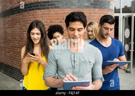 Tutti gli studenti sui loro dispositivi multimediali Foto Stock