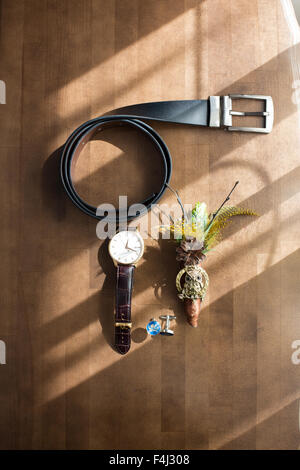 Accessori per lo sposo sul tavolo di legno sotto i raggi di luce Foto Stock