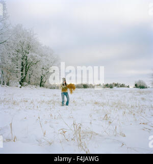 Donna con un fascio su un campo in inverno, Svezia. Foto Stock