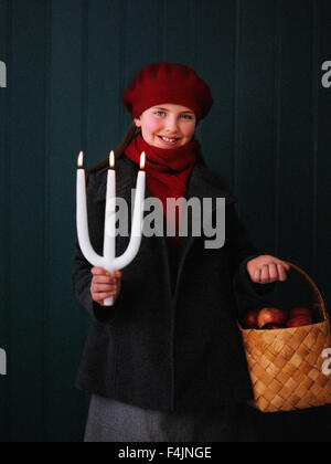 La Svezia, Stoccolma, ragazza con candela e cesto di mele Foto Stock