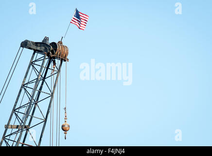 Mount Pleasant, South Carolina, Stati Uniti d'America. Xvii oct, 2015. Un American flag fissato in corrispondenza della sommità di una gru vola sopra i lavori in corso lungo Shem Creek in Mount Pleasant, Carolina del Sud. Tradizionalmente, tra American acciaio, metallo e lavoratori del ferro, il lavoro completato, in fasi diverse, è celebrata ponendo un flag di noi nel punto più alto al di sopra di un progetto. Lavoratori lungo Shem Creek sono al lavoro per sostituire un molo e il dock lungo l'uscita che sarà aperto al pubblico, in aggiunta a quello commerciale dei gamberetti per docking, come una zona di ricreazione per la visualizzazione di fauna selvatica come pure procedure Dockside pesca, stan Foto Stock