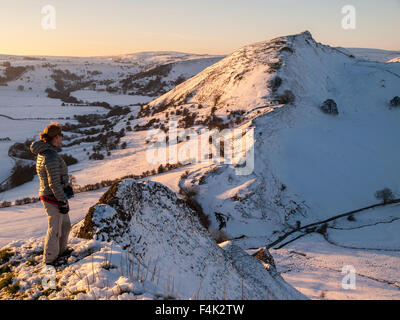 Il camminatore femmina su terreni innevati Parkhouse collina nella parte superiore della valle di colomba, Peak District con Chrome Hill a distanza Foto Stock