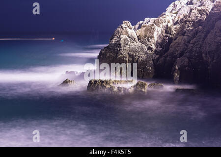 Le onde del mare linea gioco rock di impatto sulla spiaggia di notte Foto Stock