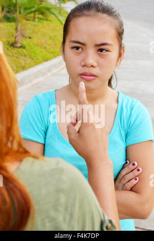 Asian adolescente guardando arrabbiato con la sua mamma mentre a discutere con lei e puntando il dito Foto Stock