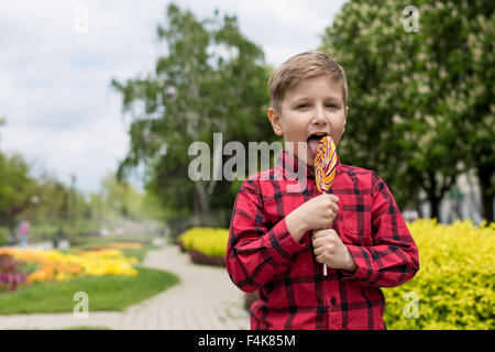 Felice ragazzino con grande candy outdoor Foto Stock