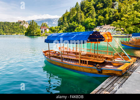 In legno barca turistica sulla riva del lago di Bled, Slovenia con il castello di Bled in background Foto Stock