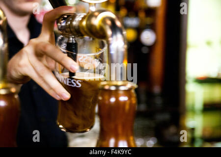 Il barista di colare una pinta di birra Guinness Foto Stock