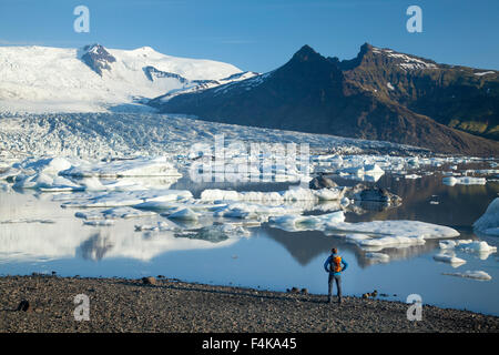 Persona accanto a Fjallsarlon laguna iceberg, al di sotto del ghiacciaio Fjallsjokull. Vatnajokull National Park, Sudhurland, Islanda. Foto Stock