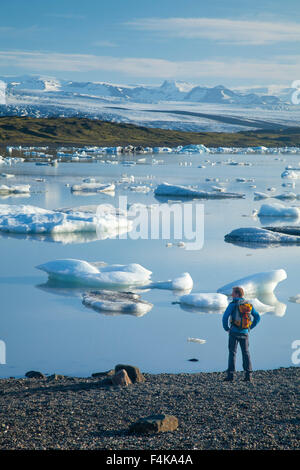 Persona accanto a Fjallsarlon laguna iceberg, al di sotto del ghiacciaio Fjallsjokull. Vatnajokull National Park, Sudhurland, Islanda. Foto Stock